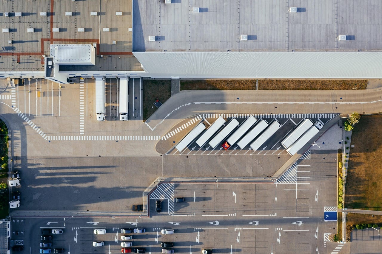 A freight depot from the air, white trailers parked in a fan beside the building